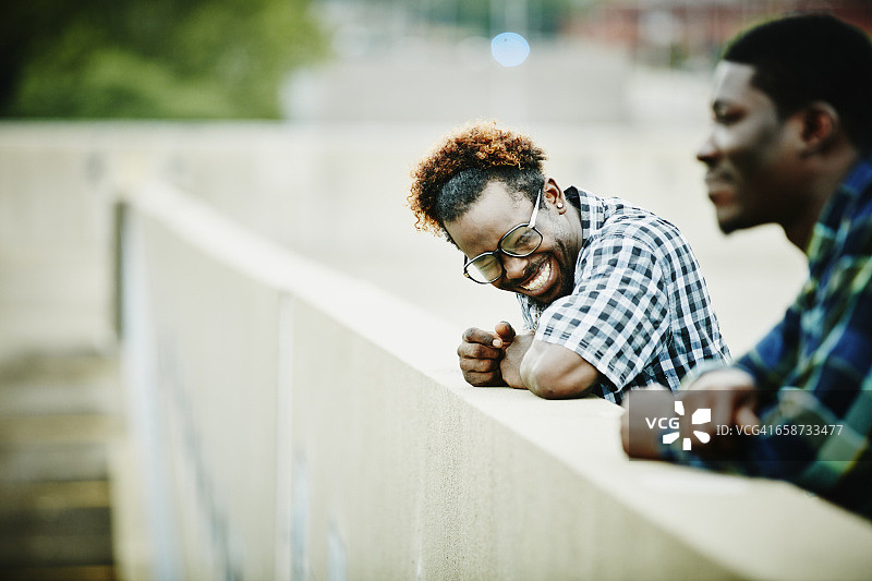 笑着靠在墙壁边缘的朋友们图片素材