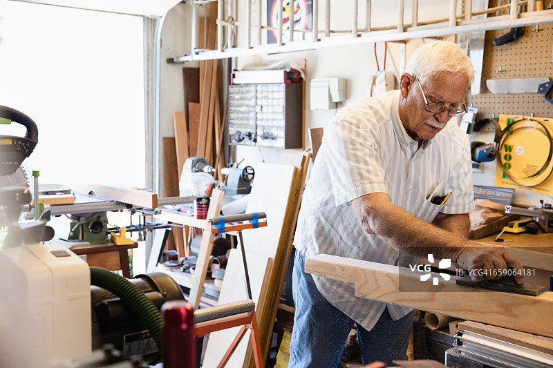年长的男人在木工坊刨木图片素材