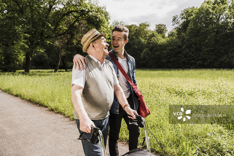 快乐的爷爷带着孙子在户外散步图片素材