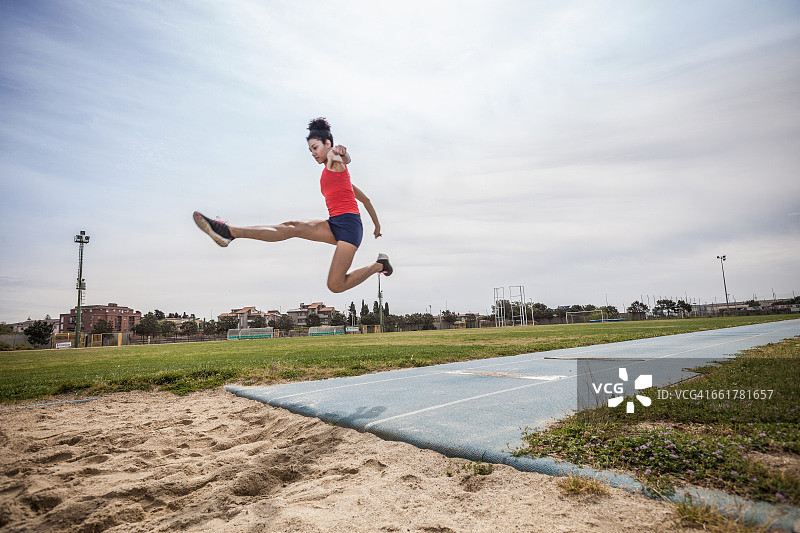 在运动设施中跳跃的年轻女子跳远运动员图片素材