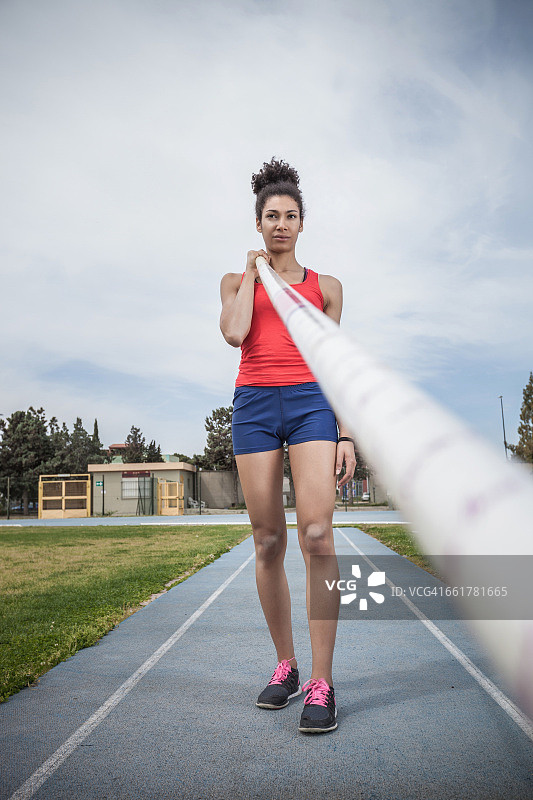 年轻女撑杆跳运动员在运动场上专注的肖像图片素材