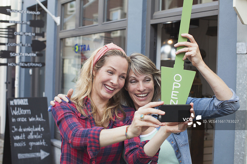 店前拿着“营业中”标牌自拍的女人图片素材