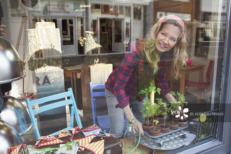 透过玻璃看到的正在布置橱窗的女人图片素材