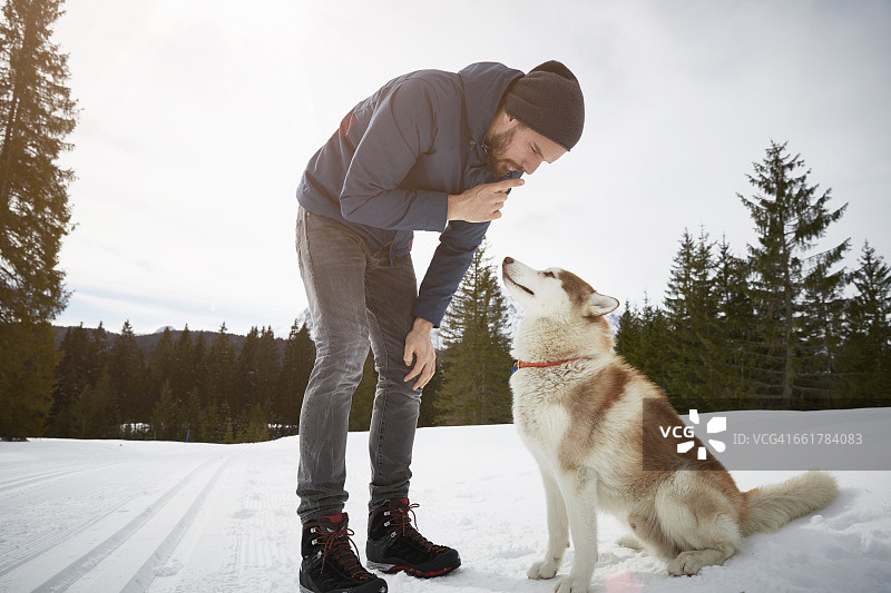 在德国巴伐利亚州埃尔毛雪景中训练哈士奇的年轻男人图片素材