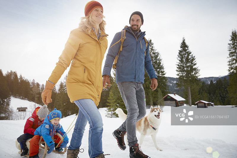 父母在冬季埃尔毛拉着儿子滑雪橇，德国巴伐利亚图片素材