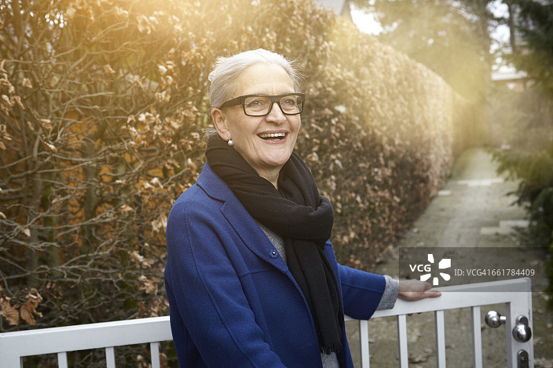 女子打开大门，看着镜头微笑图片素材