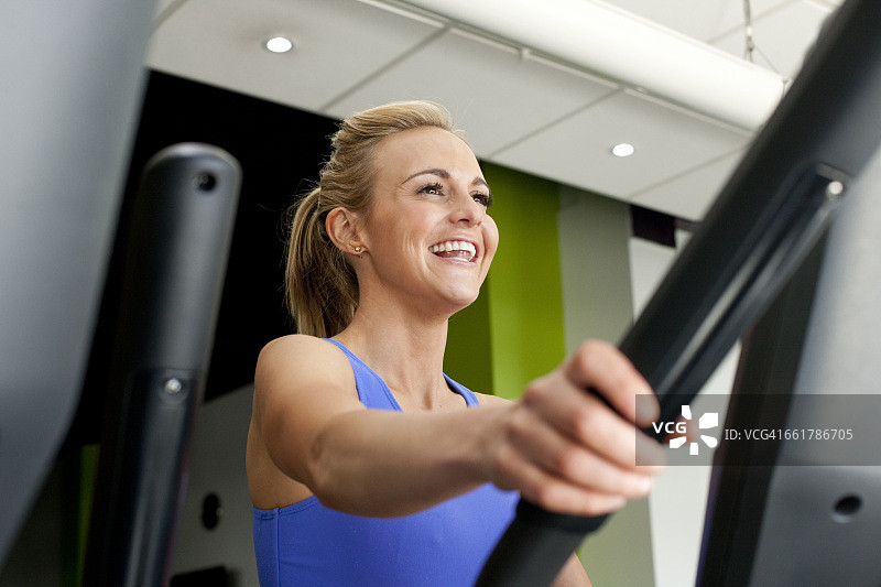 在健身房使用运动器材微笑的女人图片素材