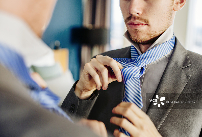 在酒店房间对着镜子系领带的商人图片素材