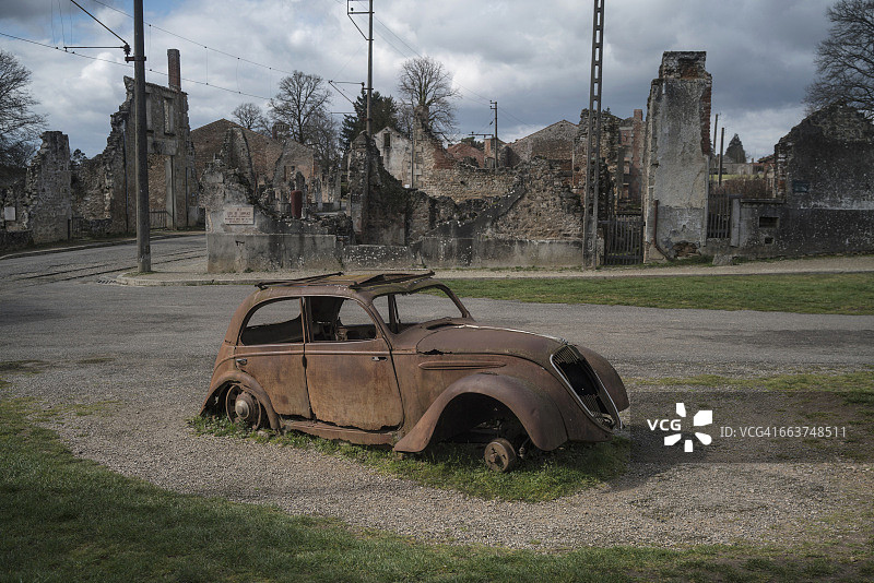 奥拉杜尔-sur-格拉讷废弃建筑旁路边的废弃汽车图片素材