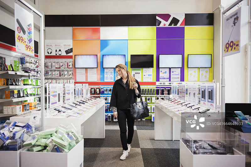 女顾客在商店里看智能手机图片素材