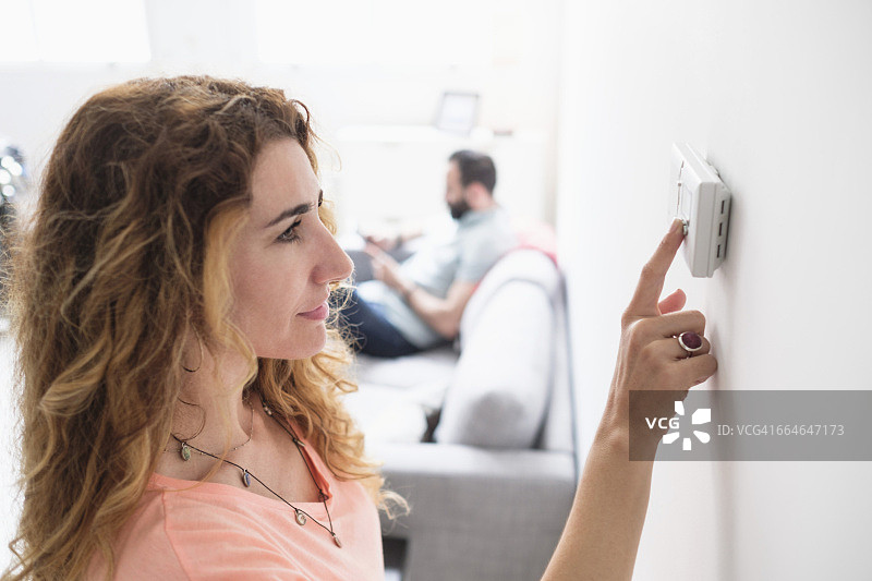 中年妇女调节恒温器图片素材