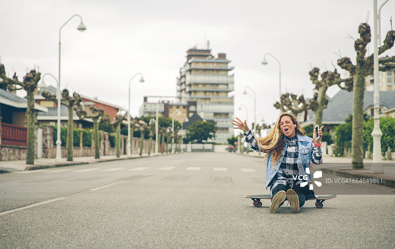 坐在滑板上听音乐的年轻女子图片素材