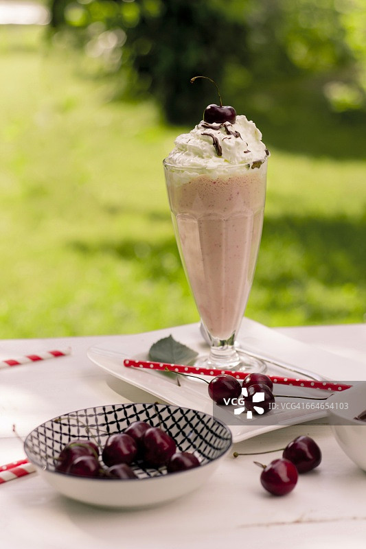 两杯香草奶昔，含香草冰淇淋和巧克力酱，碗中盛满樱桃图片素材