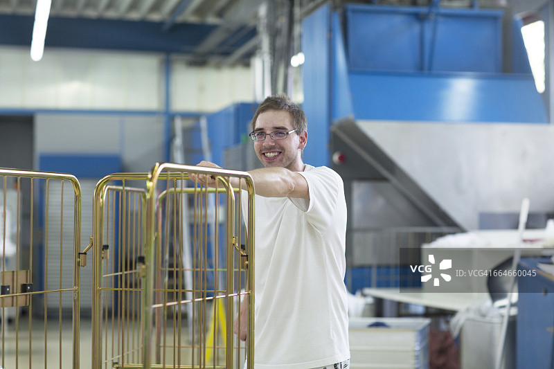 在洗衣店里推着笼车的男人图片素材