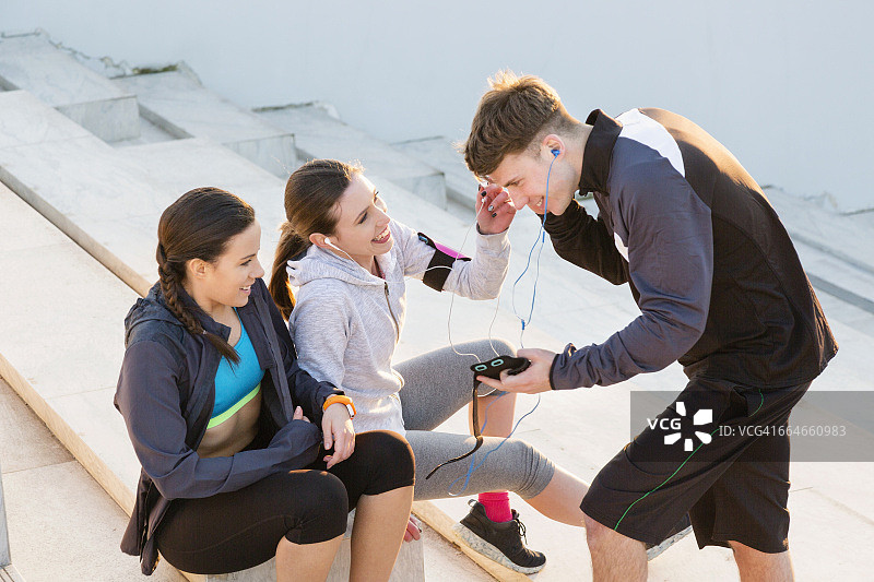三个朋友在锻炼休息时用MP3听音乐图片素材