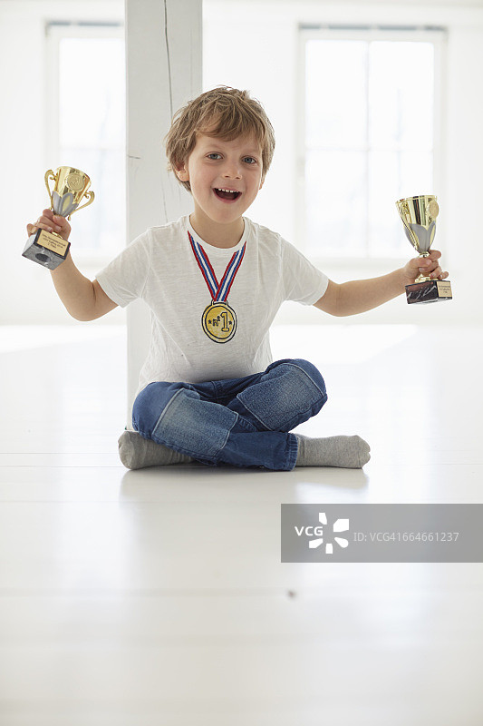 男孩手捧奖杯佩戴金牌的肖像照图片素材