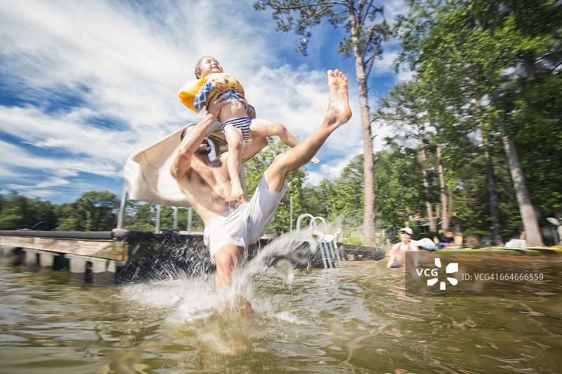 男人抱着从滑梯上跳下来的女儿，地点：美国佐治亚州杰克逊湖图片素材