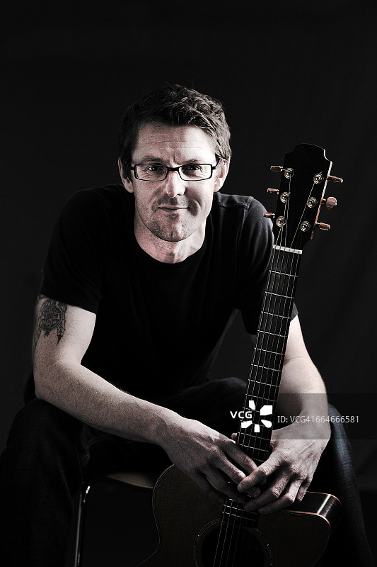 中年男人和他原声吉他的低调肖像图片素材