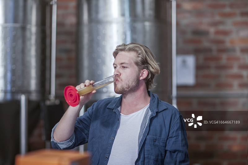 在小型啤酒厂检查精酿啤酒质量的男子图片素材