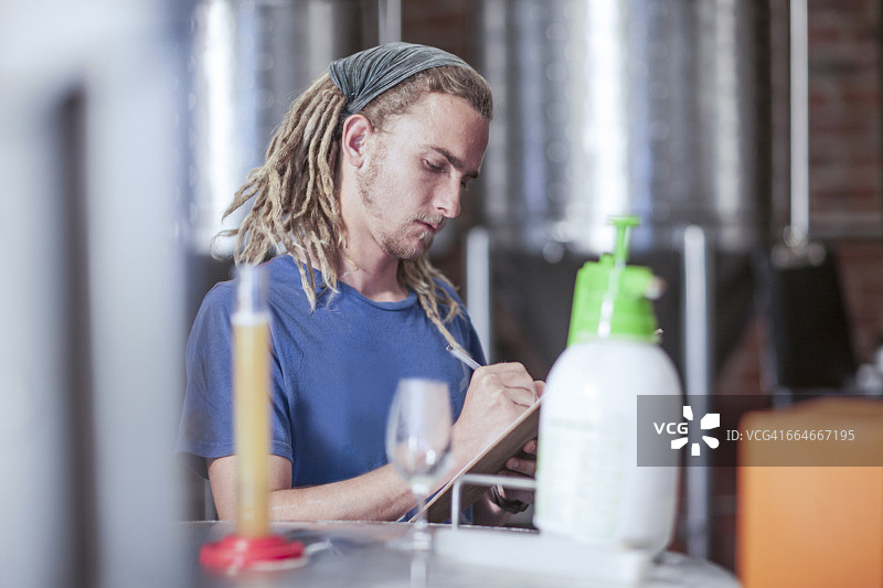在小型啤酒厂检查精酿啤酒质量的男子图片素材