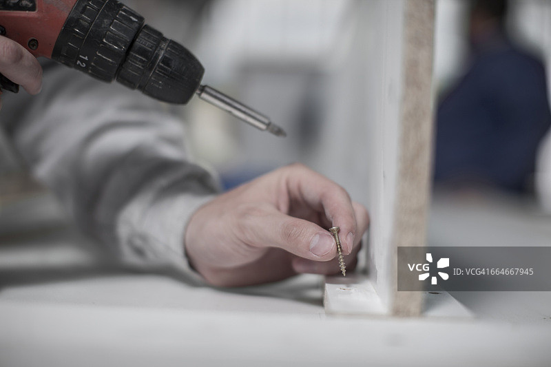 木工车间里木匠用手钻的手部特写图片素材