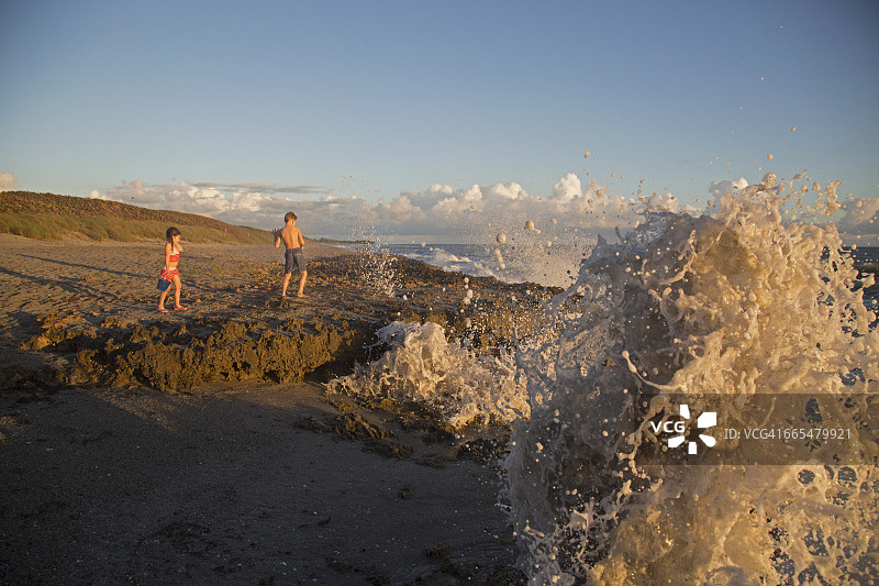 女孩和哥哥观赏海浪，地点：美国佛罗里达州朱庇特岛图片素材