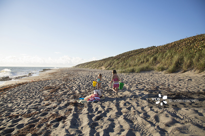 姐妹俩在美国佛罗里达州朱庇特岛吹岩保护区海滩上玩玩具桶图片素材