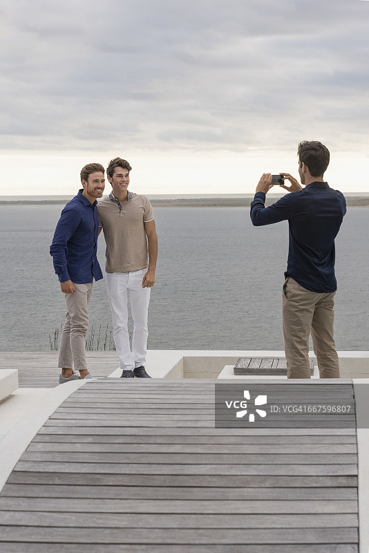 男子用手机给朋友们拍照图片素材