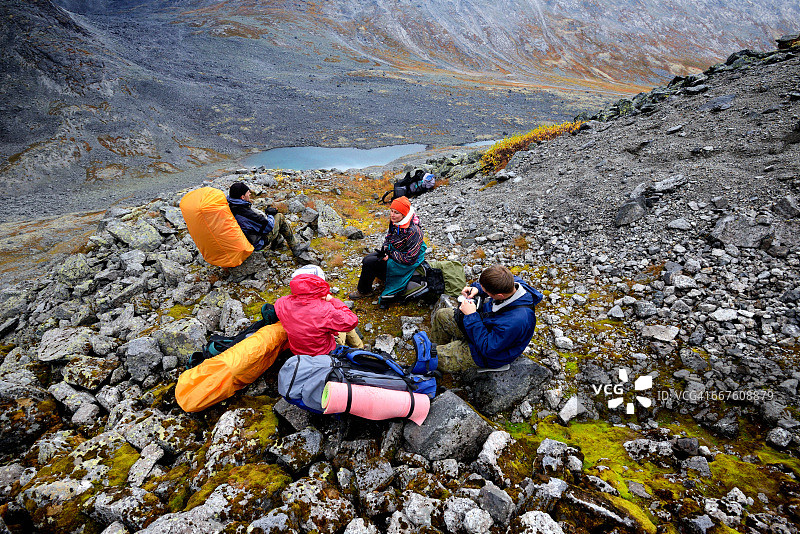 四名成年徒步者在俄罗斯科拉半岛希比内山脉崎岖的山谷中休息图片素材
