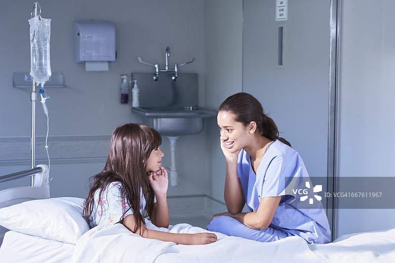 护士与坐在儿童医院病床上的一位女病人交谈图片素材
