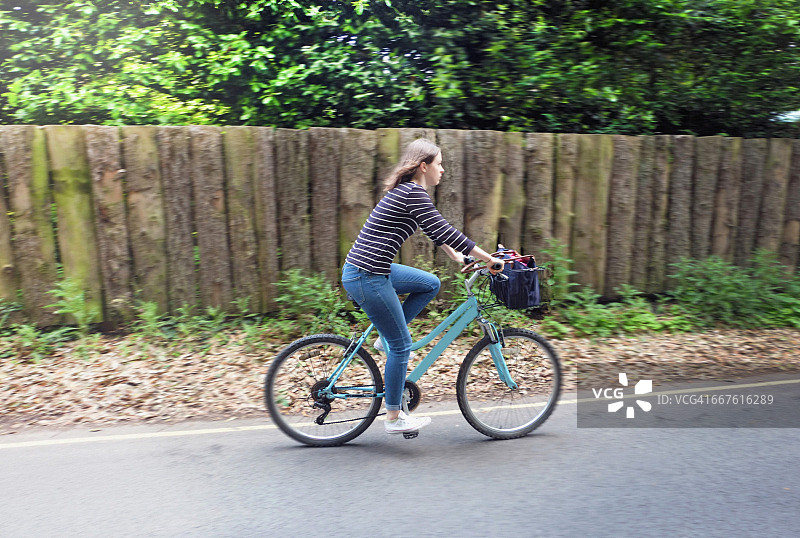 年轻女子在乡村道路上骑自行车图片素材