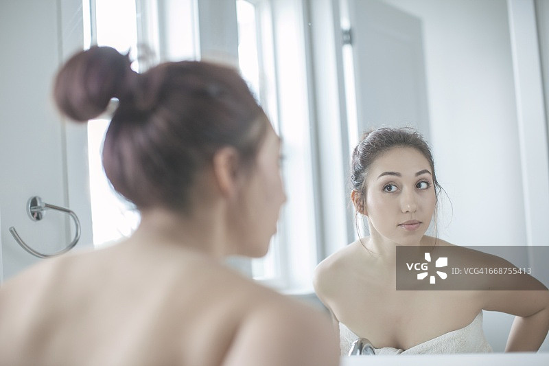 年轻女人在浴室照镜子图片素材