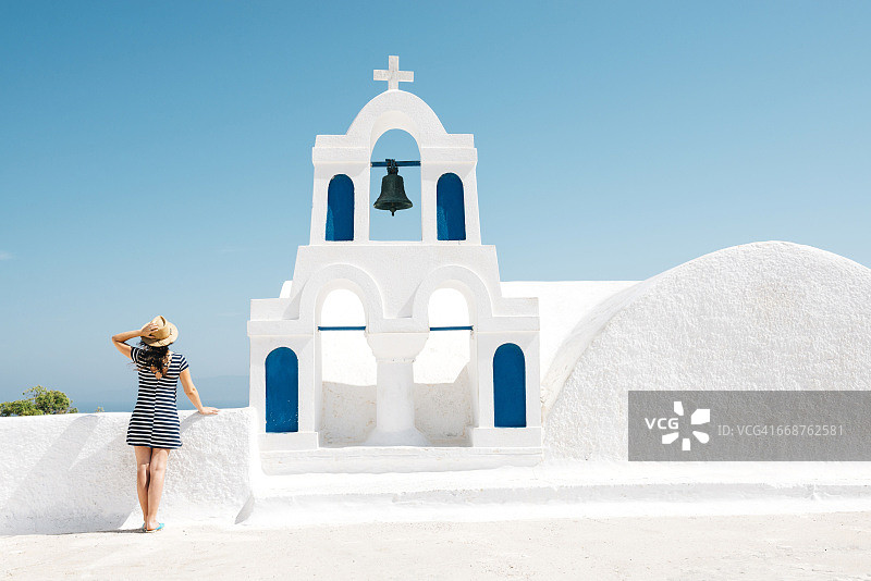 希腊圣托里尼岛伊亚：眺望大海的女子背影与钟楼图片素材