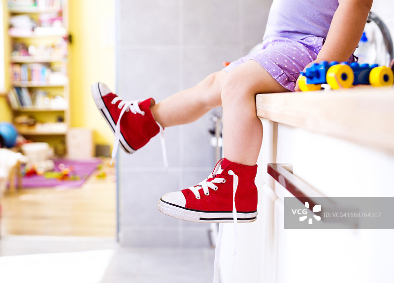 在厨房里穿着红色帆布鞋的小女孩图片素材