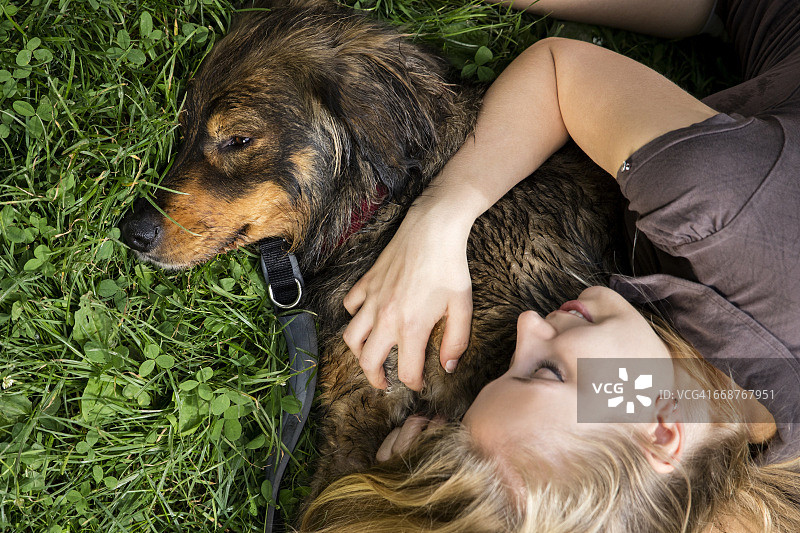 年轻女子在草地上与狗放松身心图片素材
