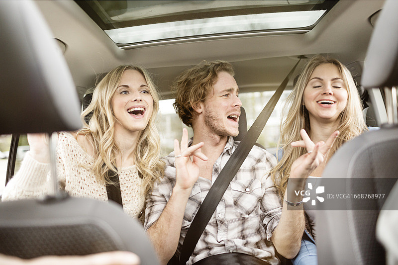 三个朋友坐在汽车后座上一起唱歌图片素材