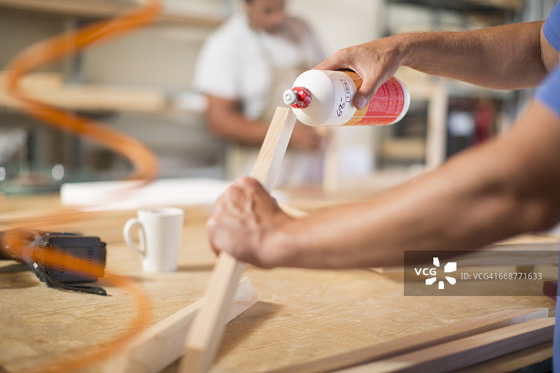 男人在帆布工作室的画框上涂胶水图片素材