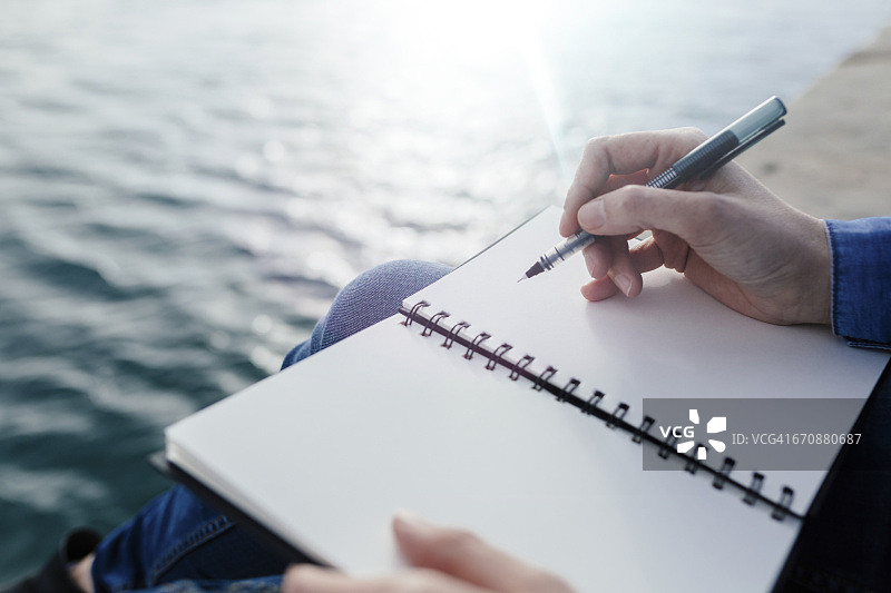 坐在码头上写笔记本的年轻女人图片素材