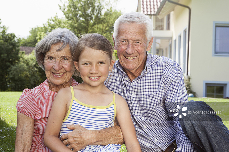 在花园里与孙女在一起的快乐祖父母的肖像图片素材