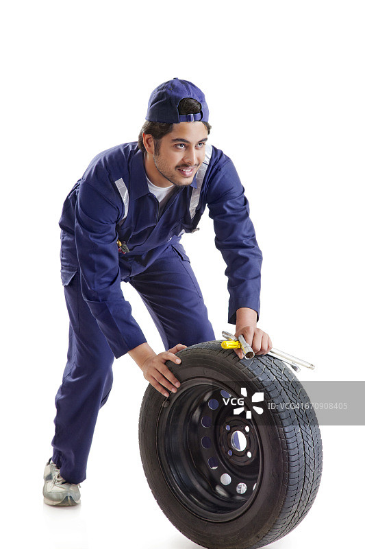 汽车修理工肖像：带着备用轮胎和手动工具图片素材