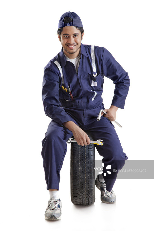 汽车修理工肖像：带着备用轮胎和手动工具图片素材