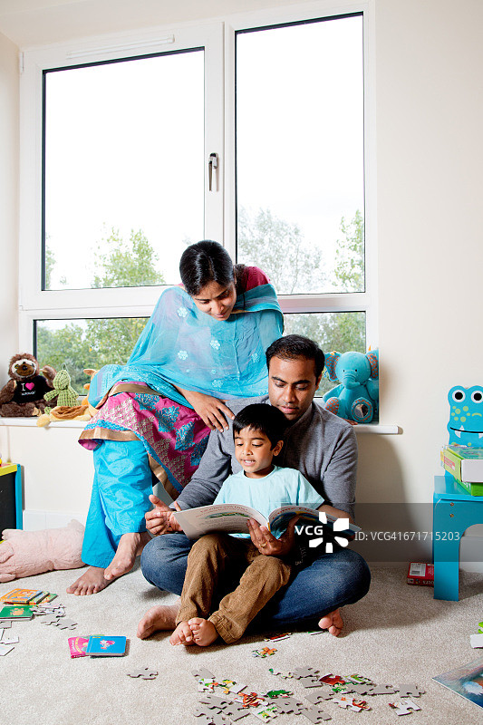 年轻的印度父母在家和儿子一起阅读图片素材
