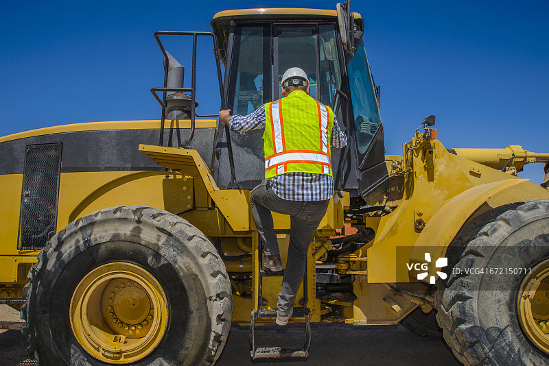 爬上推土机的白人建筑工人图片素材