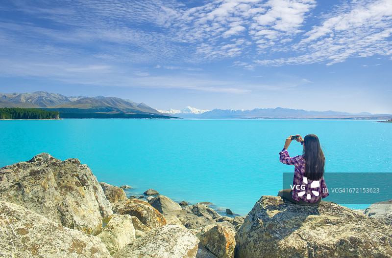 拉美裔女人穿着格子衬衫拍摄蓝色山湖图片素材
