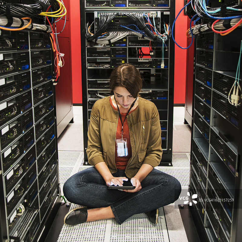 在计算机服务器机房地板上使用平板电脑的白人技术员图片素材