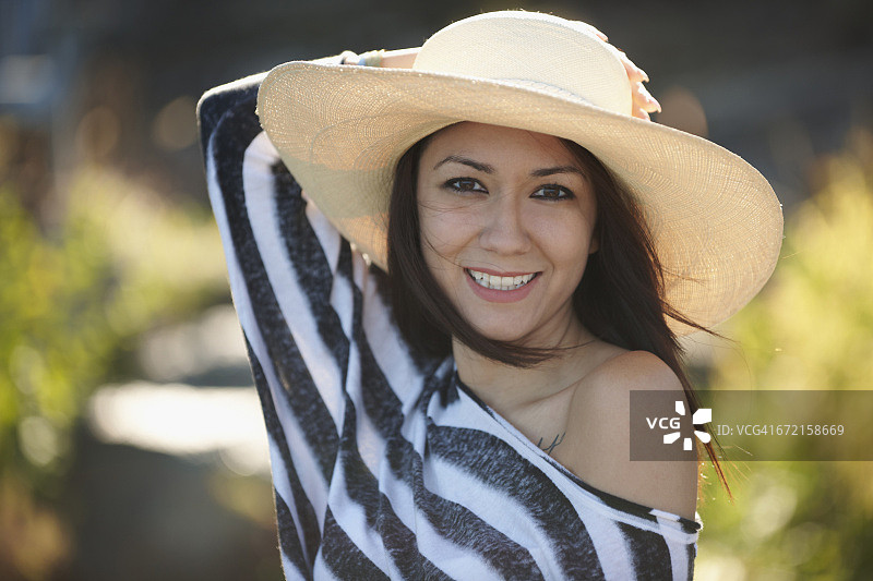 在风中拿着遮阳帽的混血女人图片素材