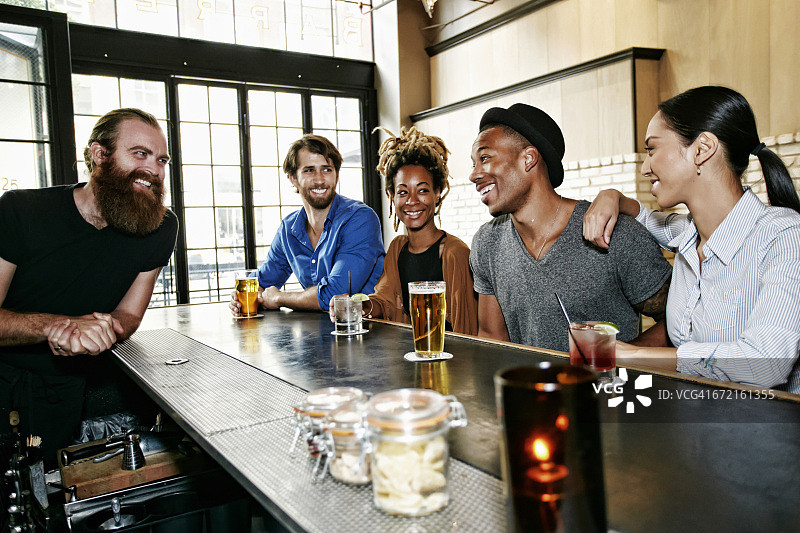 微笑的调酒师和顾客在酒吧图片素材