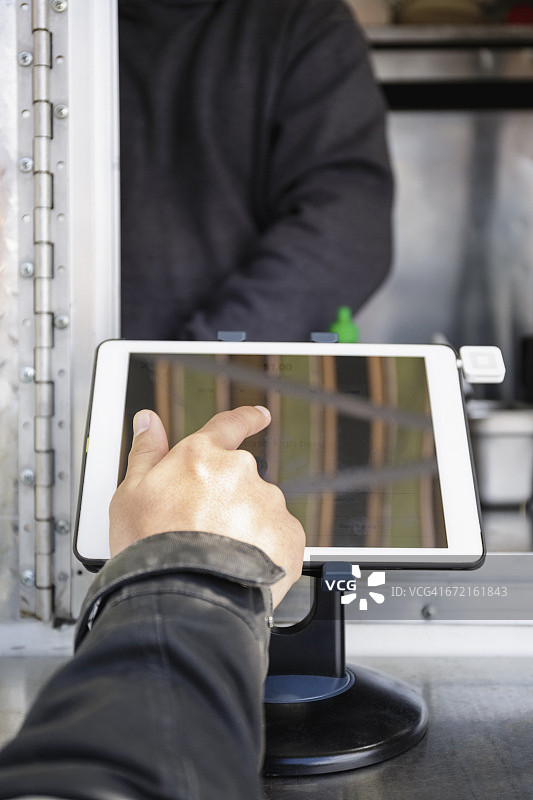 男子使用平板电脑在餐车上付款图片素材