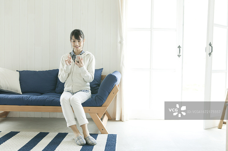 在沙发上使用智能手机的年轻女人图片素材