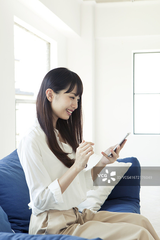 在沙发上使用手机的年轻女人图片素材